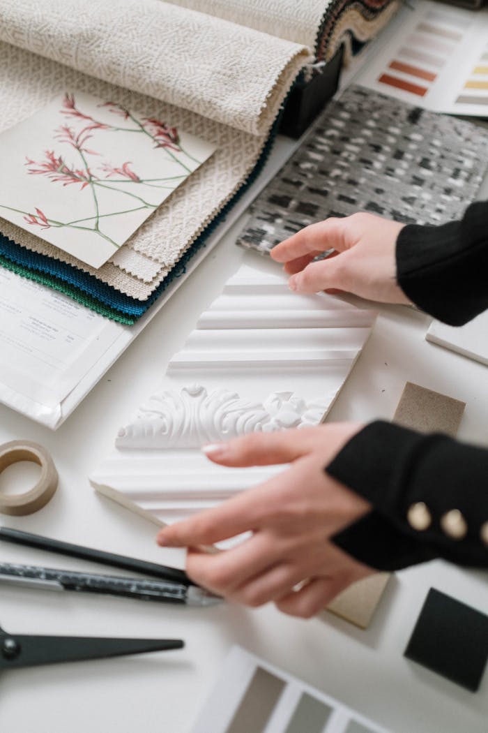 our-journey-02 Person selecting fabrics, swatches, and moldings for interior design project.